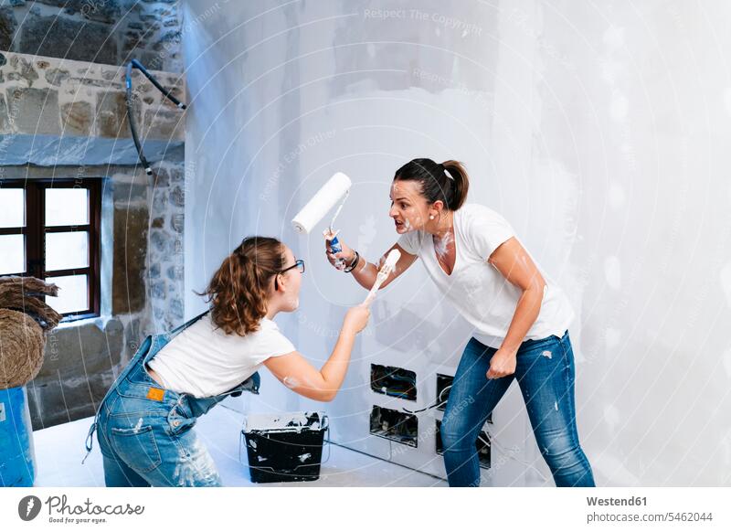 Playful mother and daughter having fun while painting a wall of her new house human human being human beings humans person persons caucasian appearance