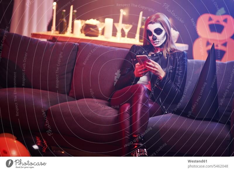 Bored woman using mobile phone at Halloween party females women hooded Party Parties Smartphone iPhone Smartphones All Hallows' Eve Boredom boring bored Adults