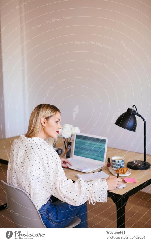 Blond businesswoman sitting at desk, working office offices office room office rooms Seated At Work blond blond hair blonde hair businesswomen business woman