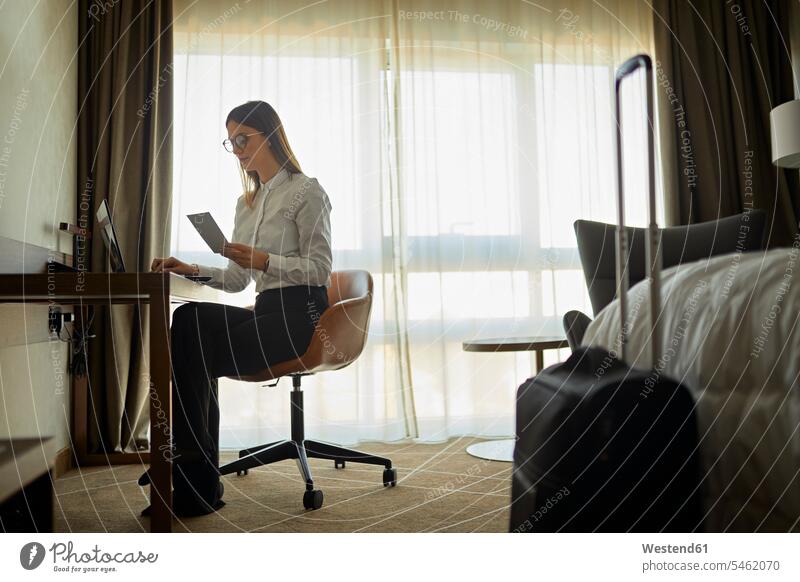 Businesswoman sitting at desk in hotel room using laptop Occupation Work job jobs profession professional occupation business life business world
