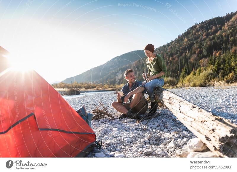 Mature couple camping at riverside in the evening light mature couple mature couples sitting Seated twosomes partnership nature experience Adventure adventurous
