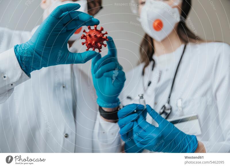 Doctors holding model of biological cell and vaccine in hospital color image colour image indoors indoor shot indoor shots interior interior view Interiors