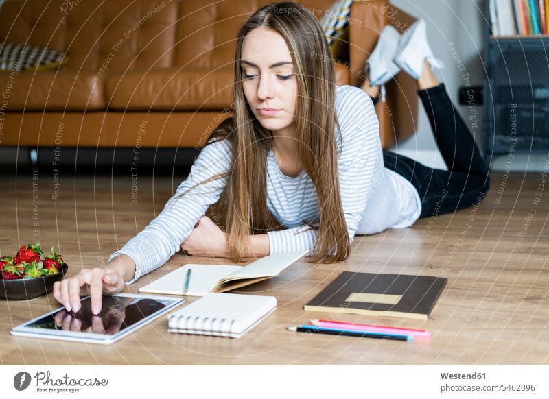 Young woman lying on the floor at home using a tablet human human being human beings humans person persons celibate celibates singles solitary people