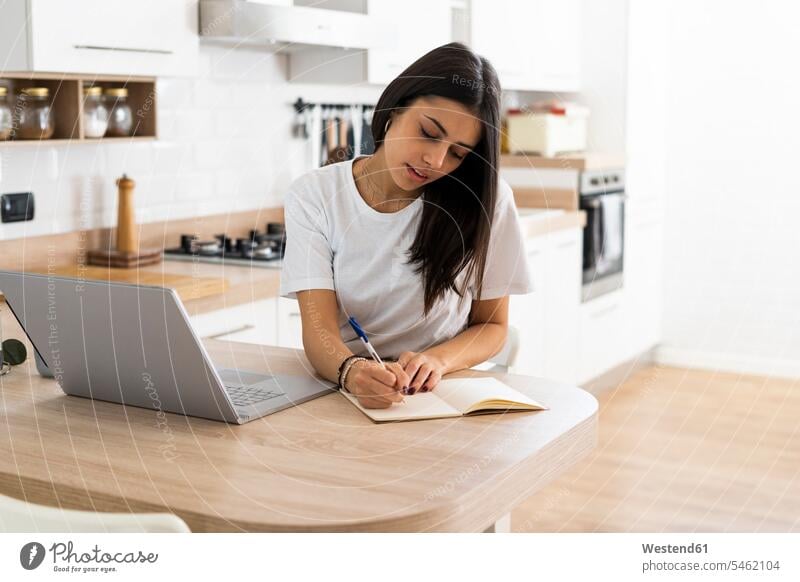 Young woman with laptop taking notes at home human human being human beings humans person persons celibate celibates singles solitary people solitary person