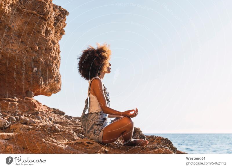 Young woman meditating at the beach Seated sit summer time summertime summery free time leisure time Distinct individual meditate meditations on the go