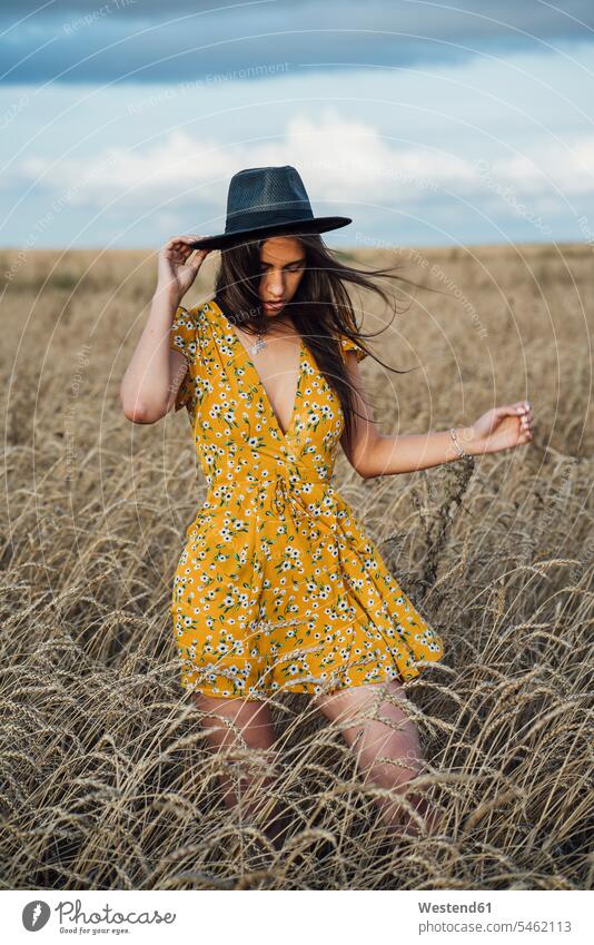 Young woman wearing summer dress with floral design and a hat dancing in corn field hats Grain field Cornfield Corn Field Cornfields Corn Fields farmland