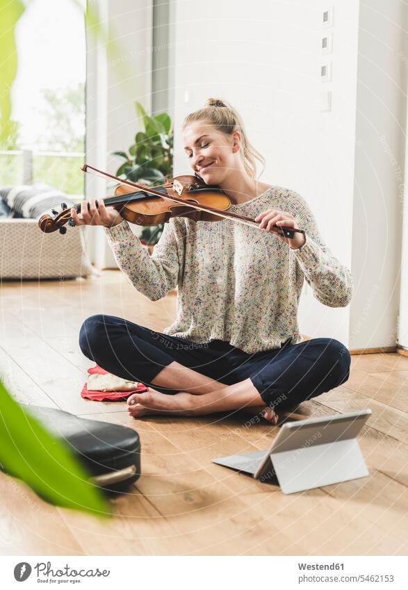 Woman with tablet sitting on the floor at home playing violin human human being human beings humans person persons celibate celibates singles solitary people