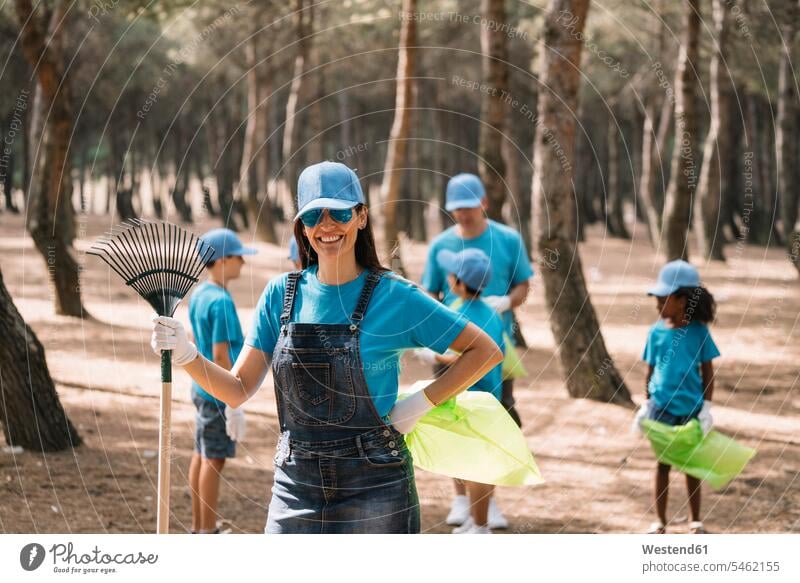 Portrait of a smiling woman with group of people collecting garbage in a park human human being human beings humans person persons caucasian appearance