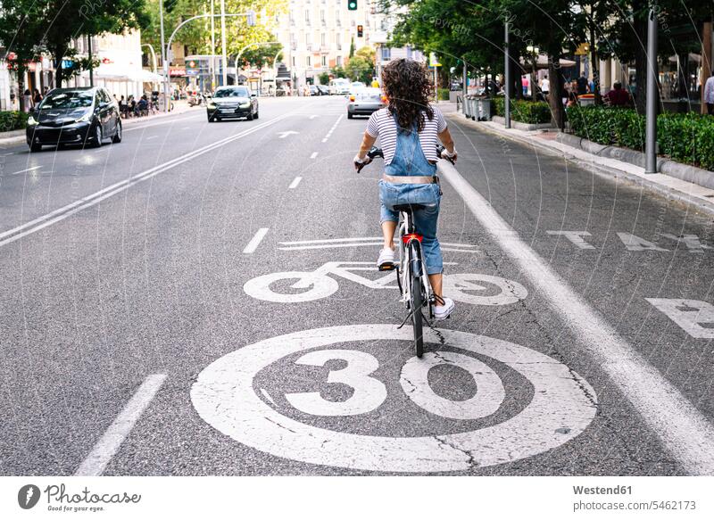 Mature woman riding on bicycle lane in city color image colour image outdoors location shots outdoor shot outdoor shots day daylight shot daylight shots