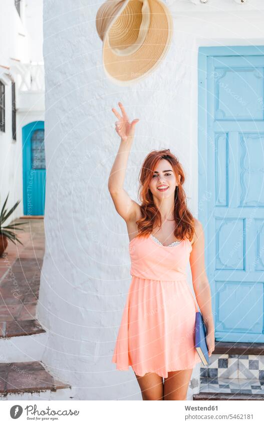 Portrait of redheaded young woman throwing her straw hat in the air, Frigiliana, Malaga, Spain books read summer time summertime summery delight enjoyment