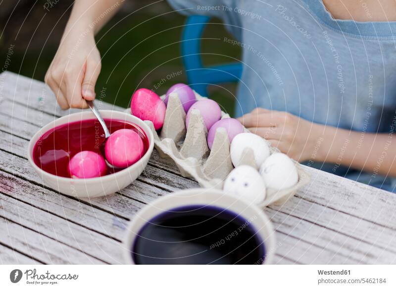 Close-up of girl dyeing Easter eggs in garden Bowls Tables Seated sit spring season Spring Time springtime colour colours magenta free time leisure time
