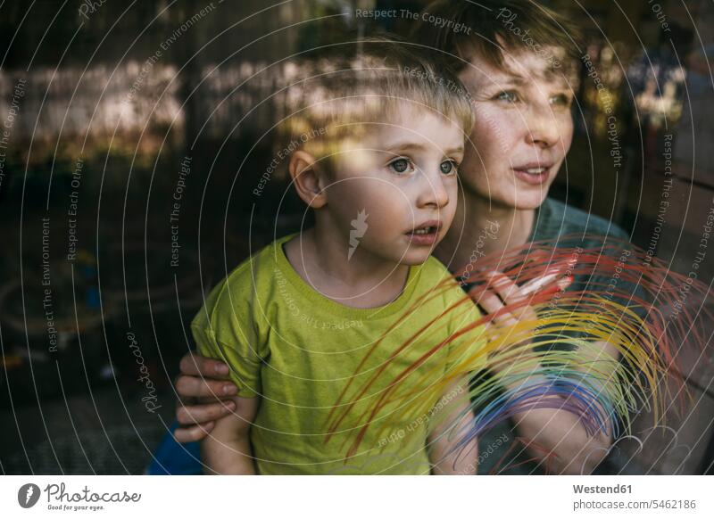 Portrait of mother and her little son looking out of window with drawn rainbow human human being human beings humans person persons families mama mom mommy