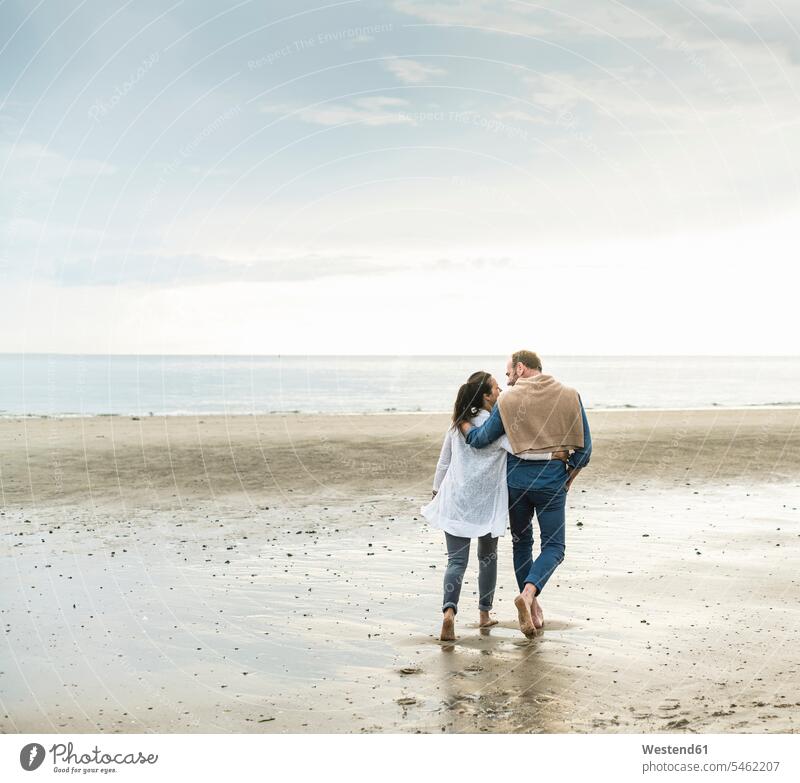 Mature couple with arms around enjoying weekend at beach against cloudy sky color image colour image Netherlands Holland The Netherlands Nederland