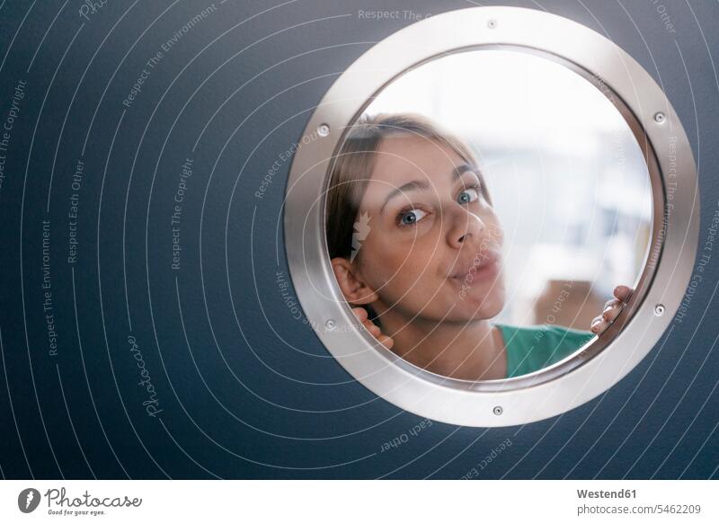 Portrait of woman peeking from behind porthole Peering Glance Glancing Peeping portrait portraits females women face human face human faces Adults grown-ups