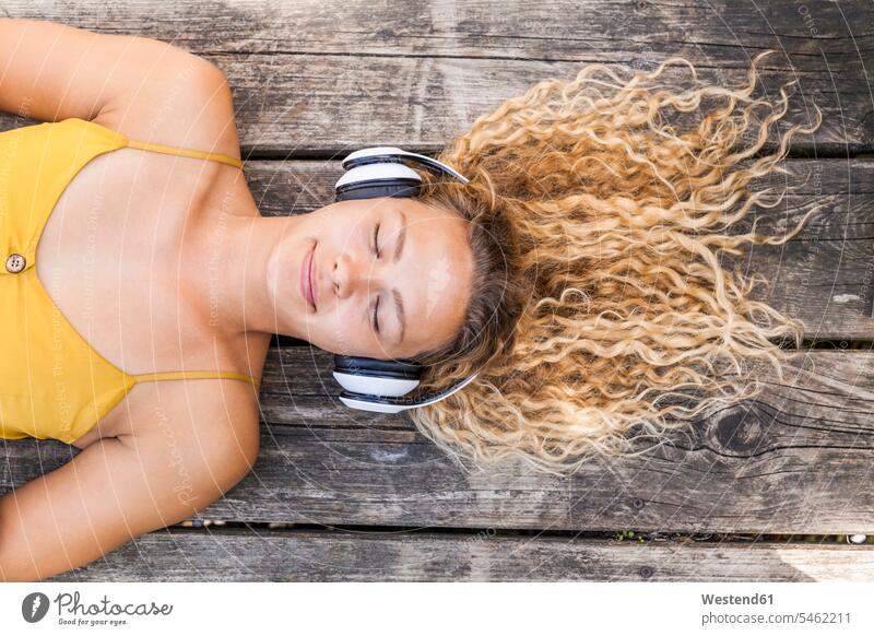 Smiling woman listening to music, lying on wood headphone headset relax relaxing hear smile relaxation delight enjoyment Pleasant pleasure indulgence indulging