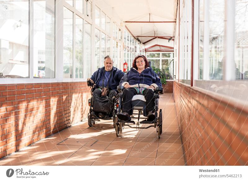 Disabled man and woman on wheelchair in corridor color image colour image indoors indoor shot indoor shots interior interior view Interiors day daylight shot