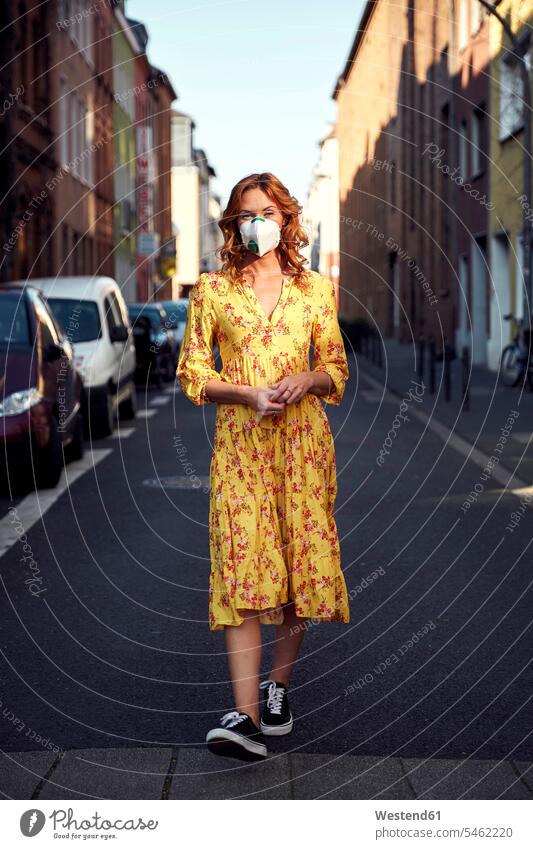 Red-haired woman wearing a FFP2 face mask and walking on empty road human human being human beings humans person persons caucasian appearance