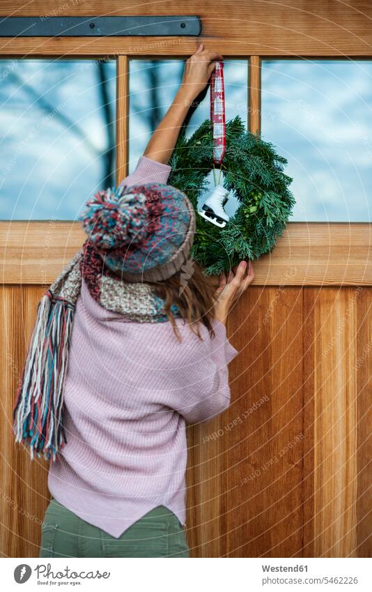 Young woman hanging wreath on house color image colour image Germany leisure activity leisure activities free time leisure time Millennials