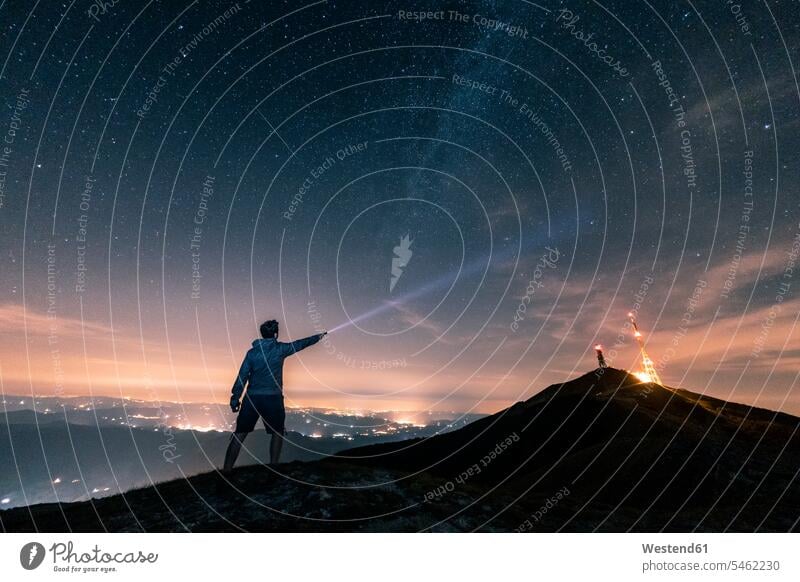 Italy, Monte Nerone, silhouette of a man with torch under night sky with stars and milky way silhouettes looking eyeing torches flashlight Milky Way men males