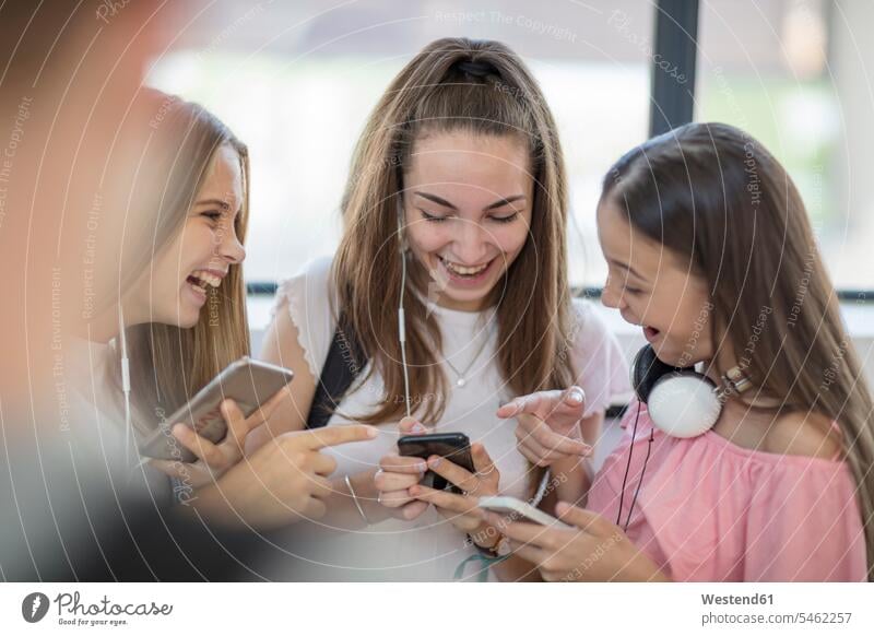 Happy teenage girls using cell phones in school schools student pupils mobile phone mobiles mobile phones Cellphone happiness happy Teenager Teens teenagers