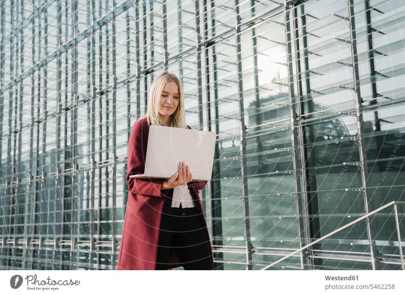 Blond businesswoman with laptop in the background of modern office building Occupation Work job jobs profession professional occupation business life