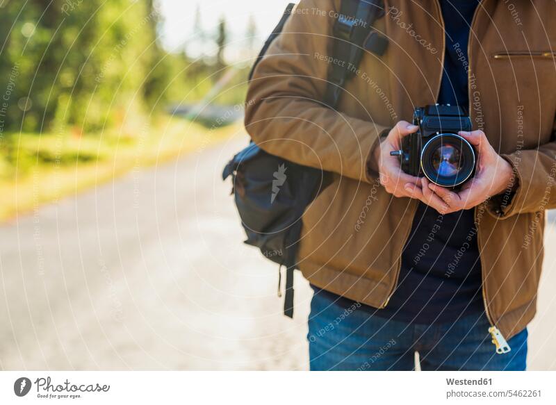Finland, Lapland, close-up of man holding camera on country road cameras rural road rural roads country roads men males streets Adults grown-ups grownups adult