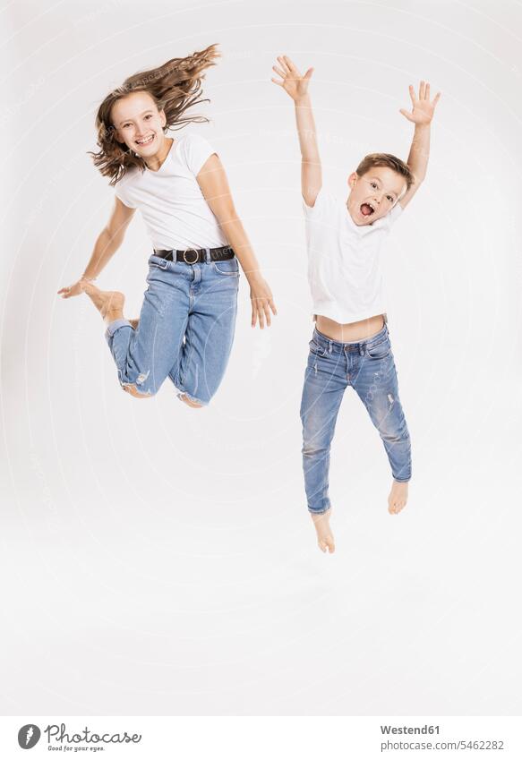 Cheerful siblings jumping against white background color image colour image casual clothing casual wear leisure wear casual clothes Casual Attire white backdrop