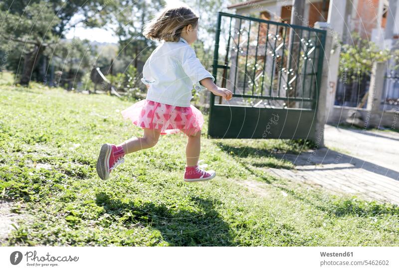 Little girl running on meadow in the garden gardens domestic garden meadows females girls child children kid kids people persons human being humans human beings