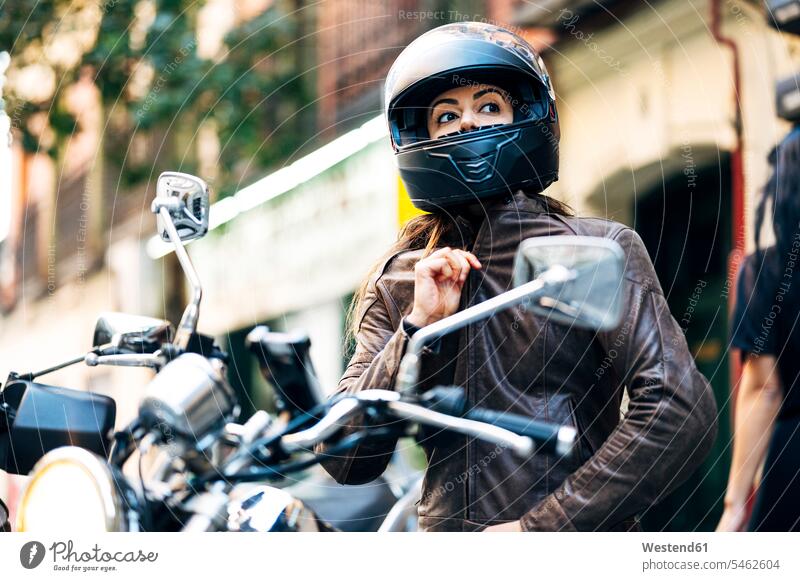 Biker woman in helmet wearing leather jacket while looking away in city color image colour image outdoors location shots outdoor shot outdoor shots day