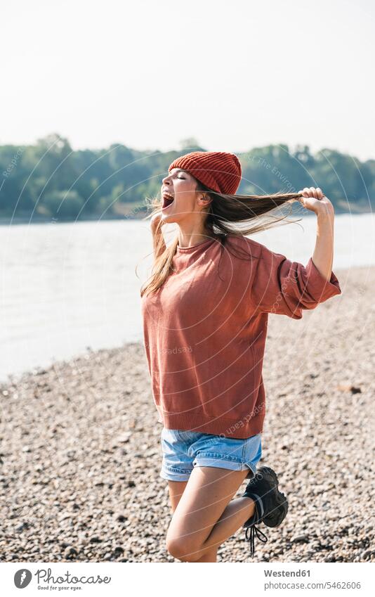 Carefree young woman screaming at the riverside riverbank carefree River Rivers females women water's edge waterside shore body of water shouting Adults