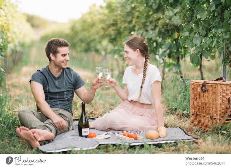 Happy young couple having picnic in the vineyards, toasting with Prosecco smile Seated sit drink delight enjoyment Pleasant pleasure happy Emotions Feeling