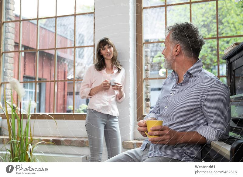 Mature couple at home taking a break, talking and drinking coffee Coffee twosomes partnership couples speaking Taking a Break resting Drink beverages Drinks