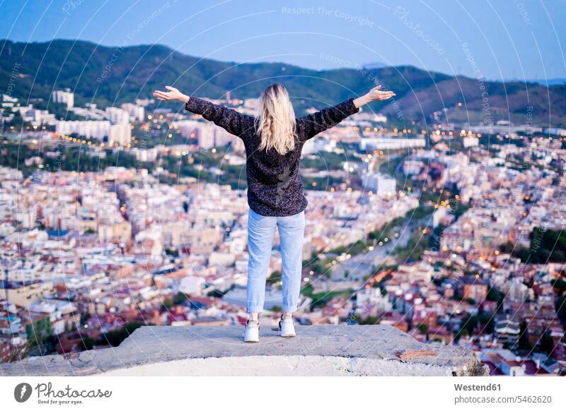 Rear view of carefree young woman standing above the city at sunrise, Barcelona, Spain human human being human beings humans person persons caucasian appearance