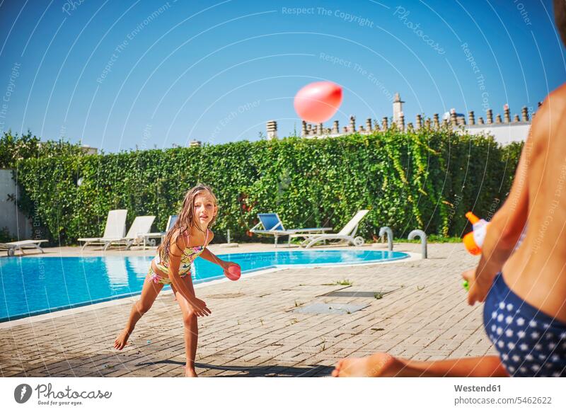 Girl and boy having a water fight with water gun and water bombs at the poolside pool edge Pool Side Water gun Water guns squirt gun squirtguns Water Pistols