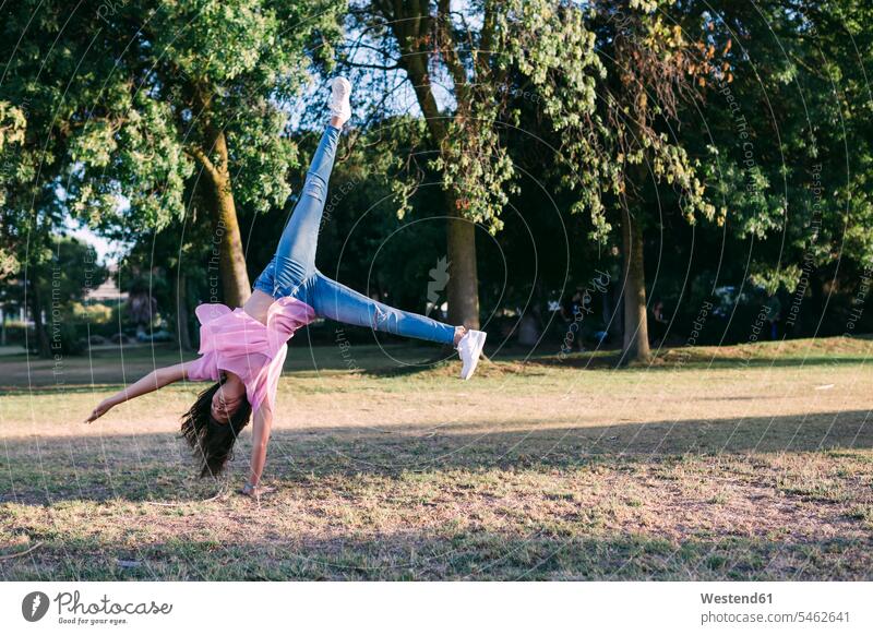 Girl doing cartwheel on land against trees in park color image colour image Portugal leisure activity leisure activities free time leisure time casual clothing