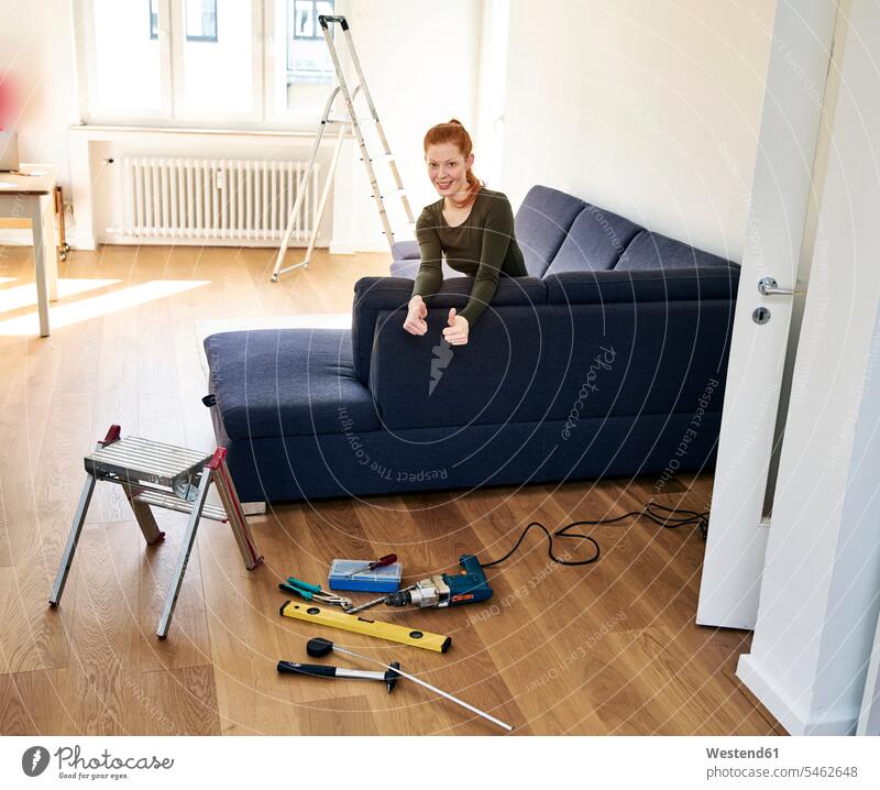 Redheaded woman with tools in the living room Tool Kit living rooms livingroom females women redheaded red hair red hairs red-haired device devices