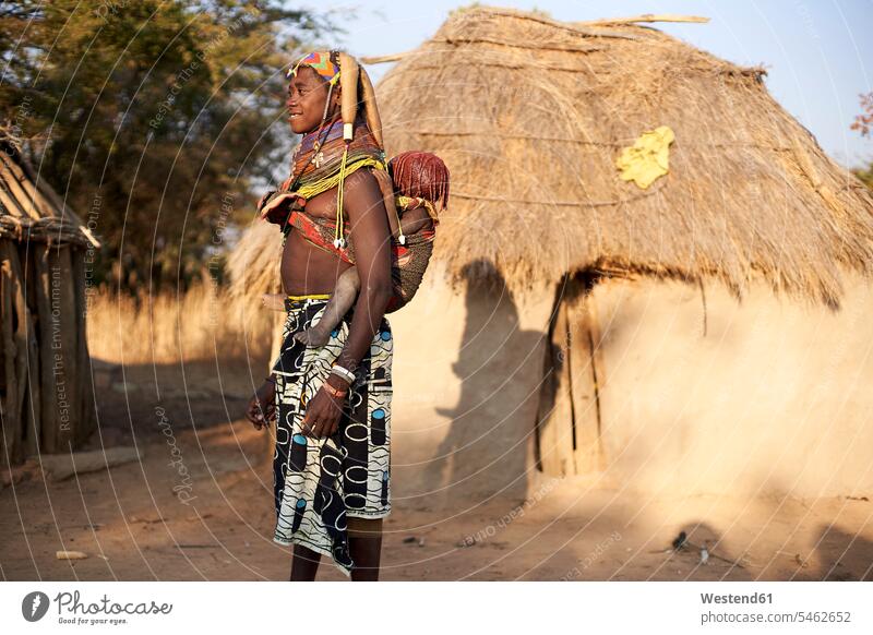 Muhila tribe woman carrying her child on her back, Kehamba, Chibia, Angola Villages traditional Traditions building buildings built structures huts