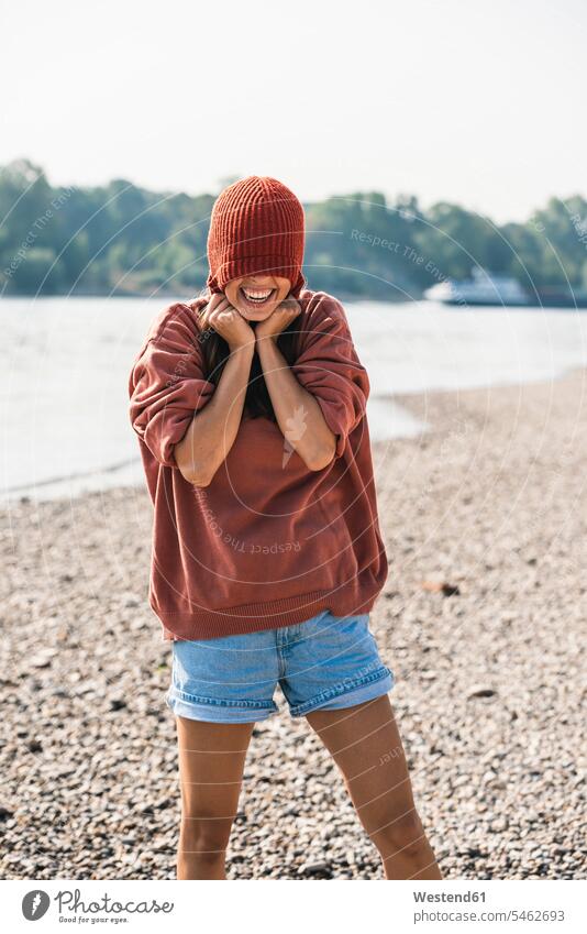 Carefree young woman wearing wooly hat at the riverside riverbank woolly hat Wooly Hat Knit-Hat Knit Hats wool cap River Rivers females women carefree