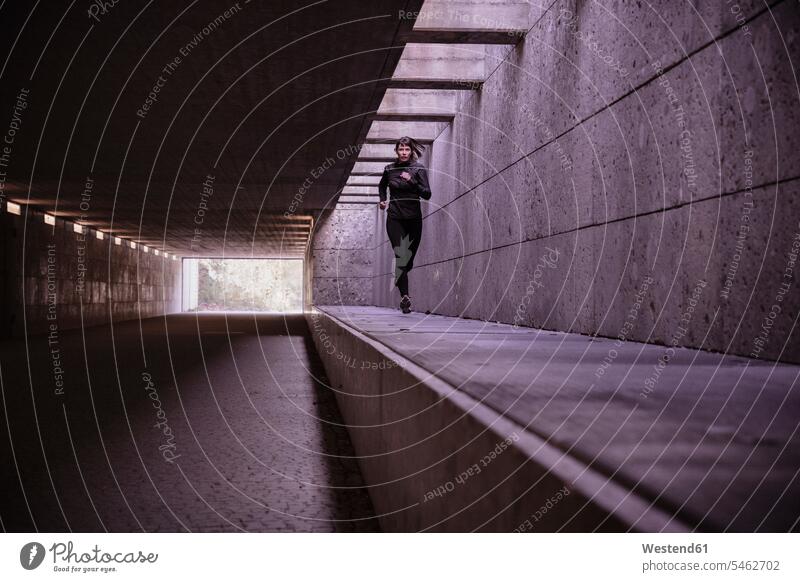 Female athlete running through pedestrian underpass human human being human beings humans person persons caucasian appearance caucasian ethnicity european 1