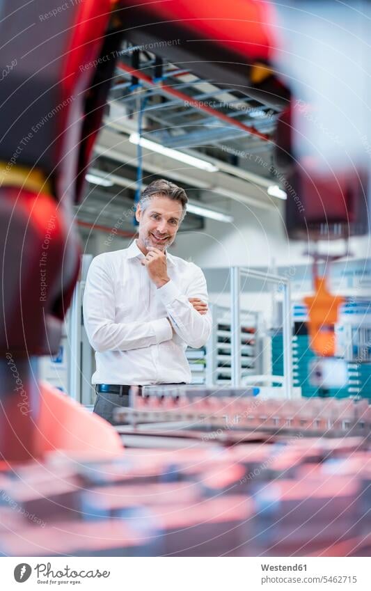 Smiling businessman in a modern factory hall looking at robot human human being human beings humans person persons caucasian appearance caucasian ethnicity