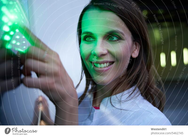 Close-up of smiling woman touching green led touchscreen heads faces human face human faces illumination shine smile Contented Emotion pleased colour colours