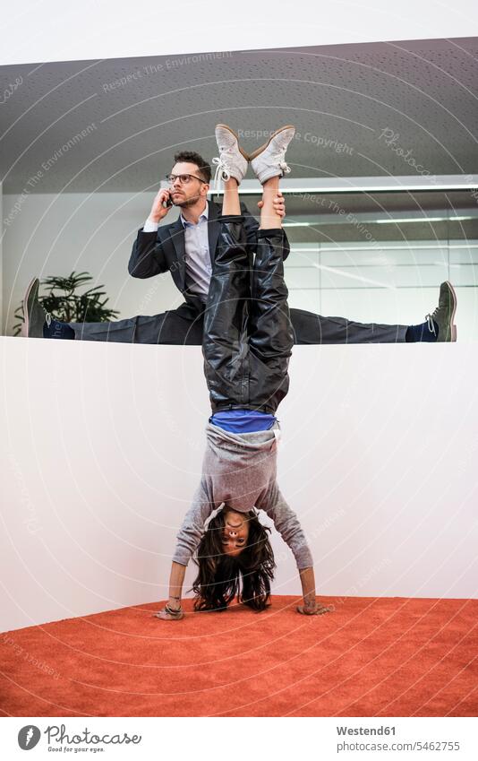 Businessman in office holding woman's legs doing a handstand human human being human beings humans person persons caucasian appearance caucasian ethnicity