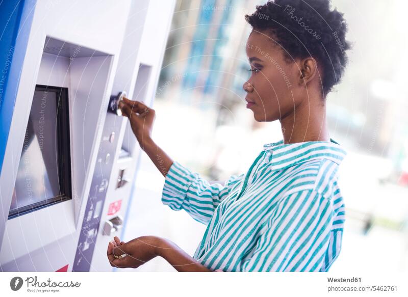 Woman at ticket machine woman females women Adults grown-ups grownups adult people persons human being humans human beings inserting standing travelling