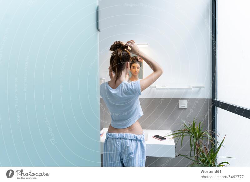 Rear view of young woman in bath room basin basins mirrors telecommunication phones telephone telephones cell phone cell phones Cellphone mobile mobile phones