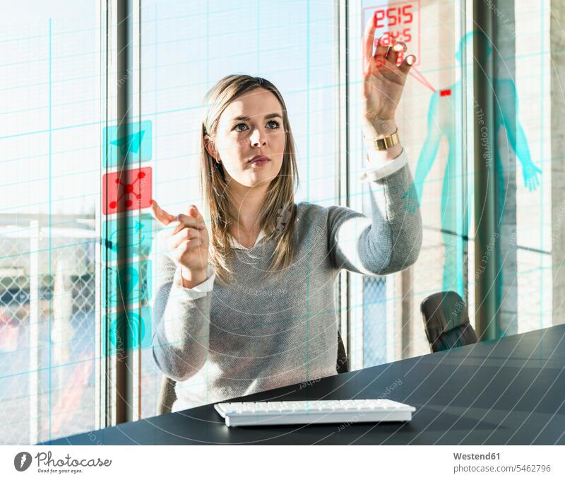 Young businesswoman touching projection screen with data in office businesswomen business woman business women offices office room office rooms business people