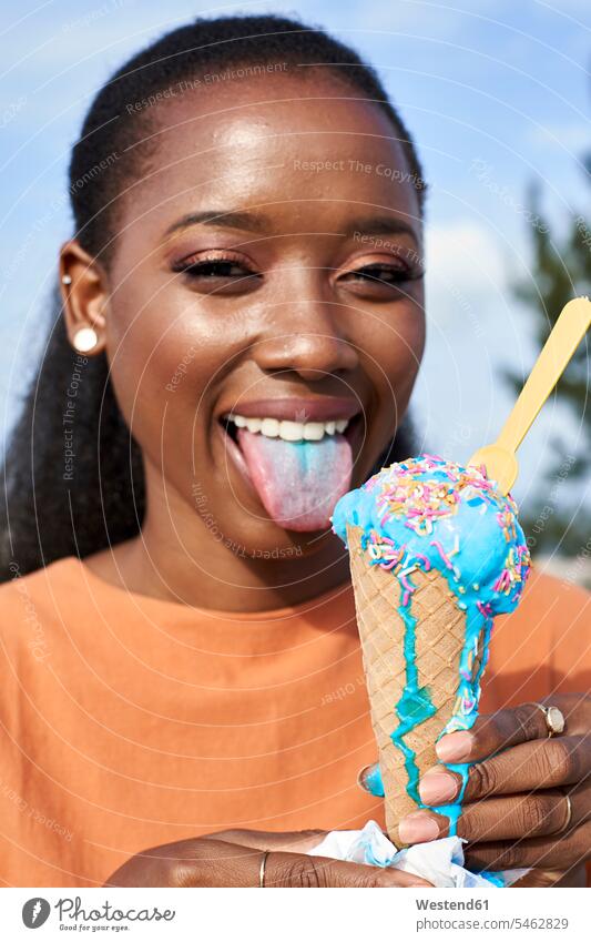 Portrait of young woman with lightblue icecream sticking out tongue tongues females women protruding protrude portrait portraits mouth mouths people persons