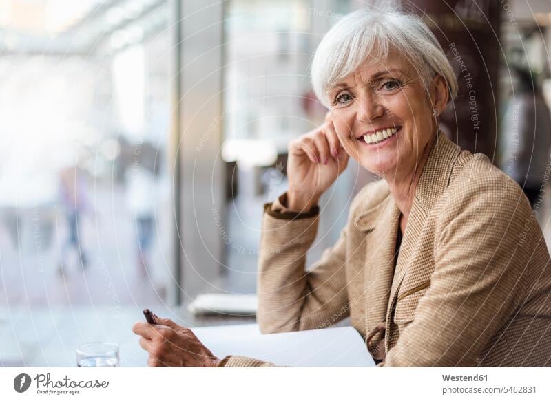 Portrait of smiling senior businesswoman with notebook in a cafe businesswomen business woman business women females senior women elder women elder woman old