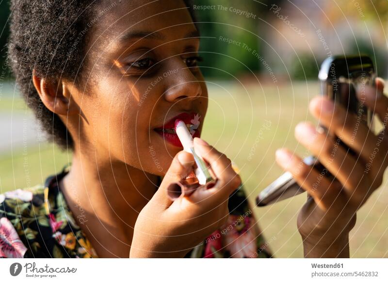 Portrait of young woman applying lipstick outdoors portrait portraits Lipstick Lipsticks females women Beauty Adults grown-ups grownups adult people persons