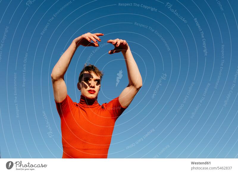 Non-binary man with hand raised dancing against clear sky color image colour image outdoors location shots outdoor shot outdoor shots day daylight shot