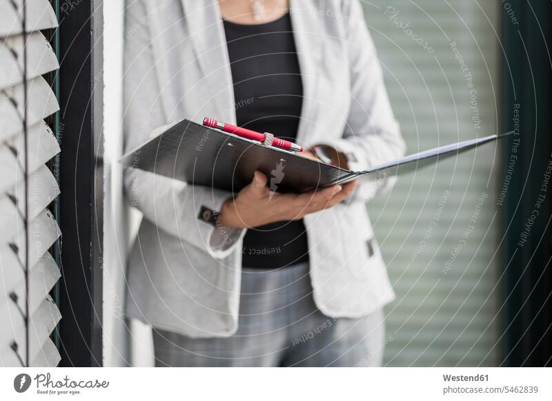 Female entrepreneur standing with file in office color image colour image businesswoman businesswomen business woman business women business people